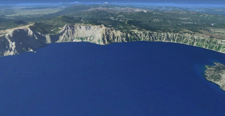 Crater Lake, Oregon — the deep-blue caldera lake ringed by steep pale rim cliffs and forested slopes.