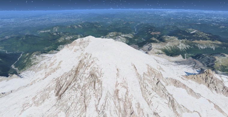 The glacier-capped summit dome of Mount Rainier, Washington, with the forested Cascade Range receding into atmospheric haze.